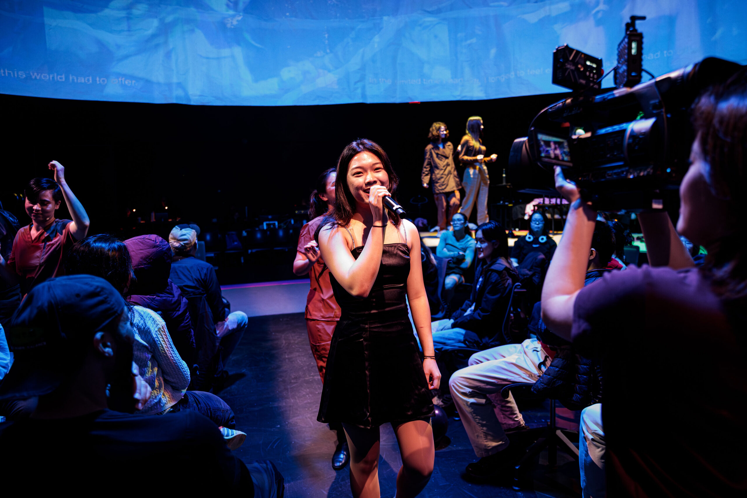 Student performer holding a microphone and walking through a performance space.