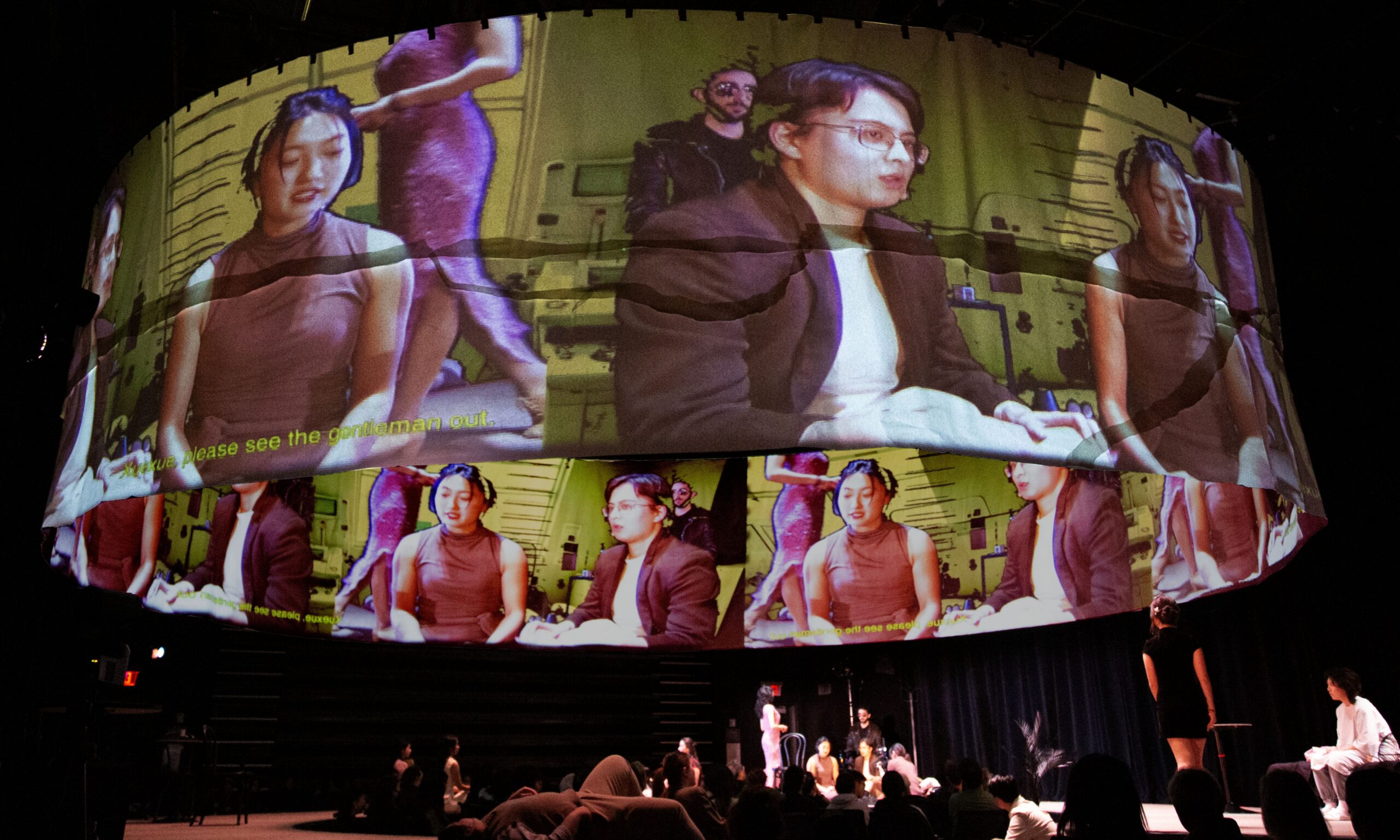 Production photo from A Dream Like a Dream. A cylindrical projection screen showing images. There is yellow text projected on it but it is difficult to read what the words say.