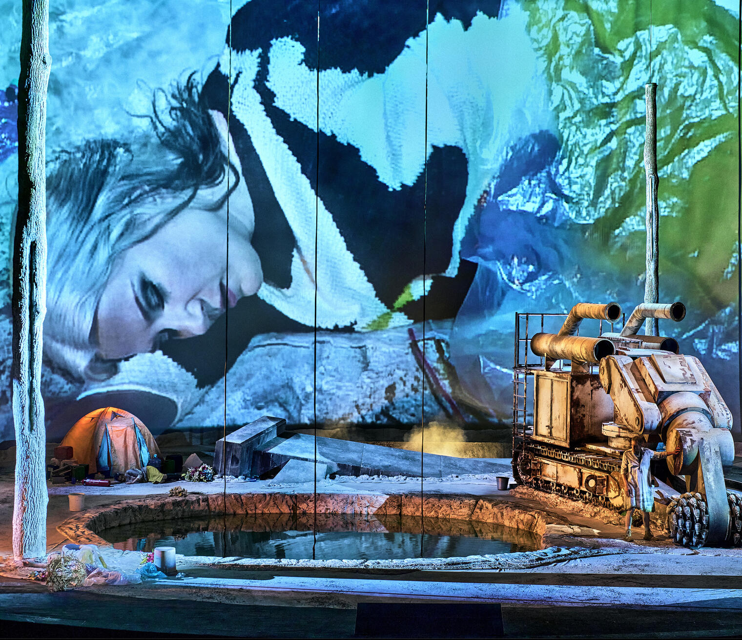 Production photo from Parsifal. A woman's image projected large on back wall of a futuristic stage set.