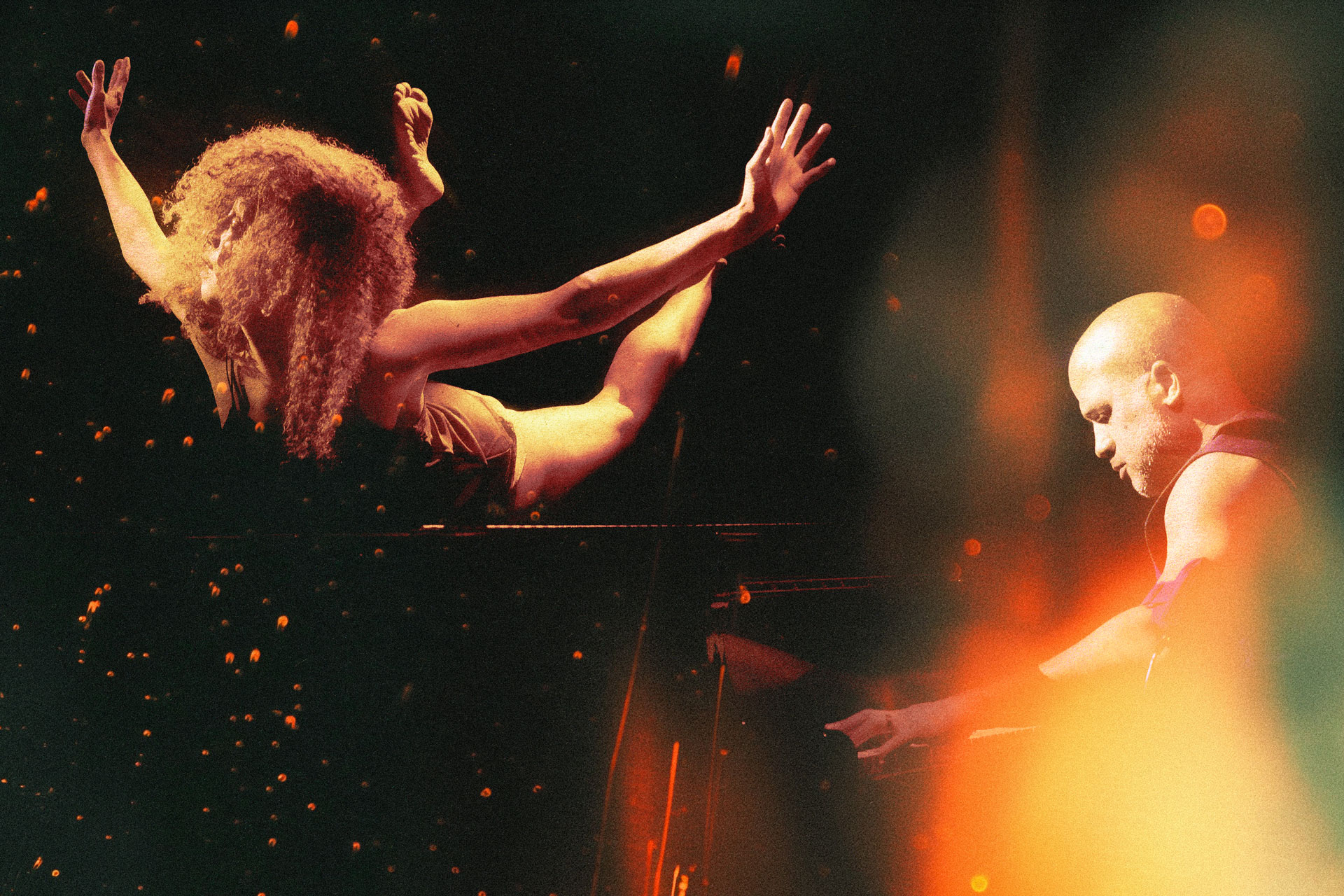 CLOSE UP. A woman on her stomach with her limbs in the air and a man playing piano.