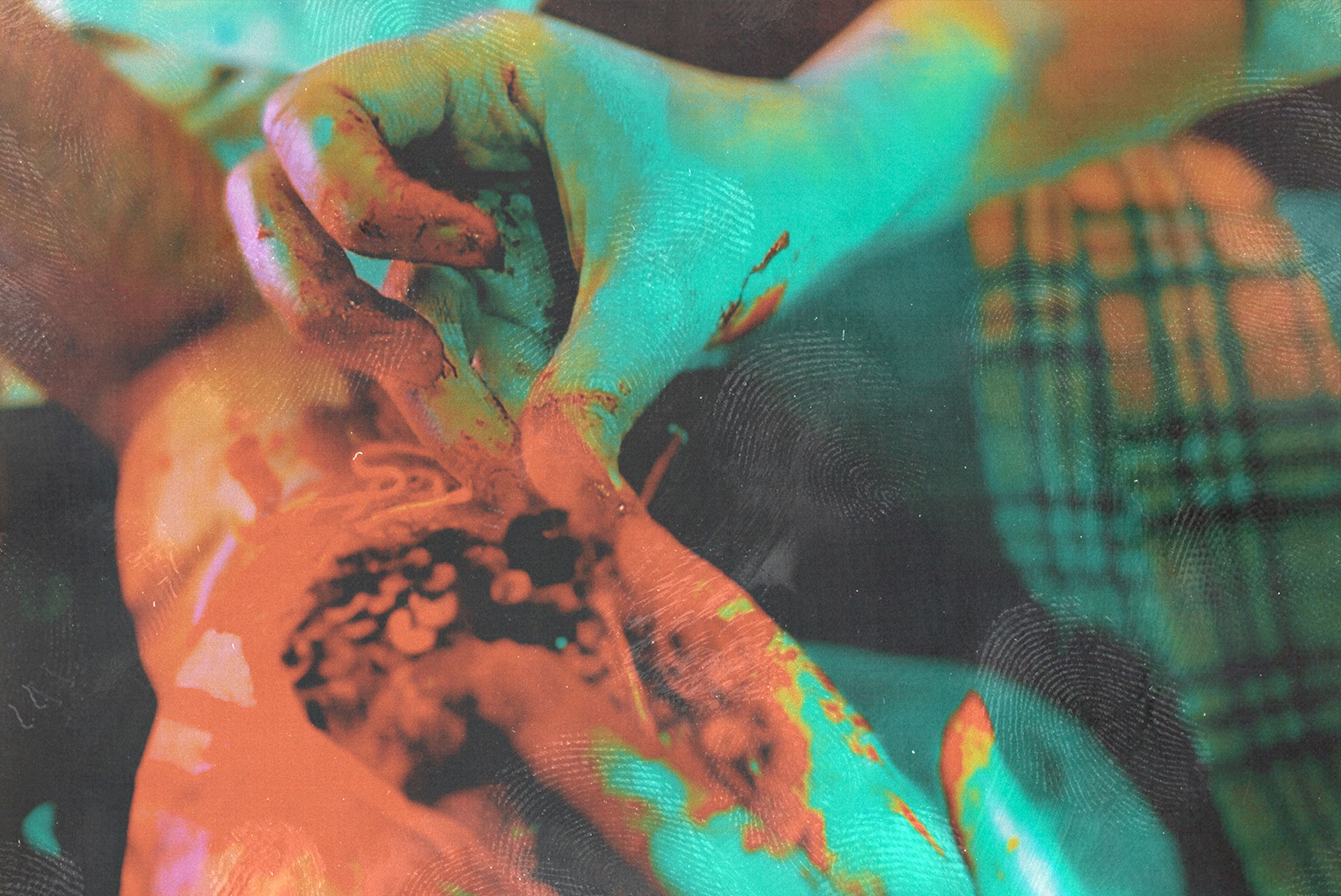 Faux-bloody hand theatrically sewing sequins onto an arm covered in stage blood.