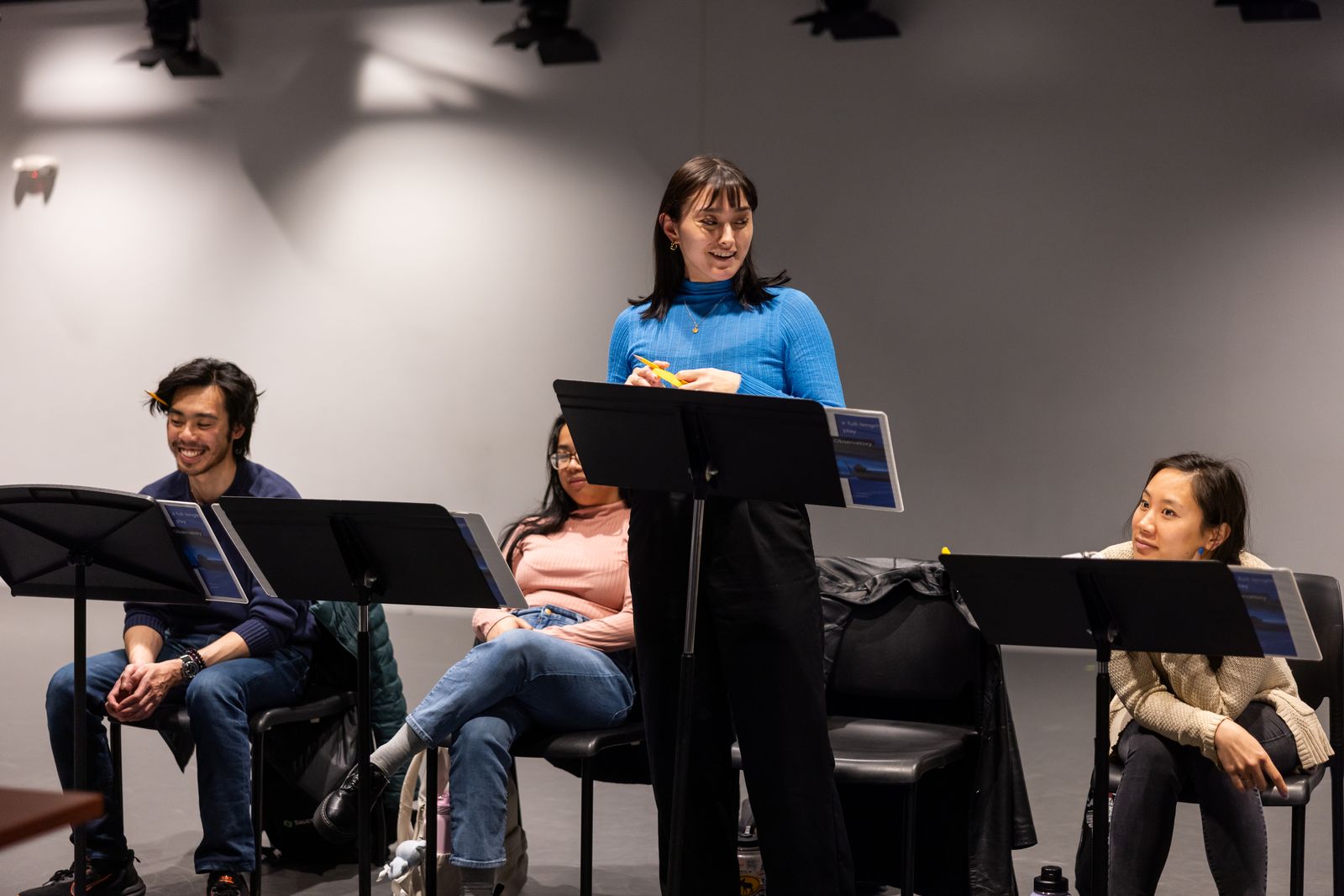 Person standing to read during staged reading of a play script.