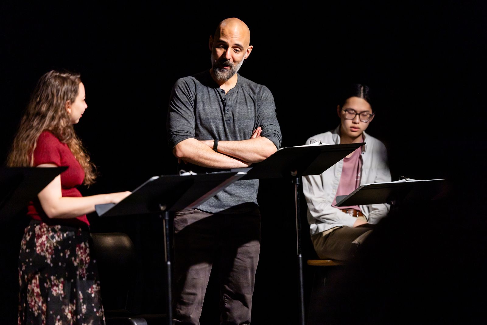Three people during staged reading of a play script.